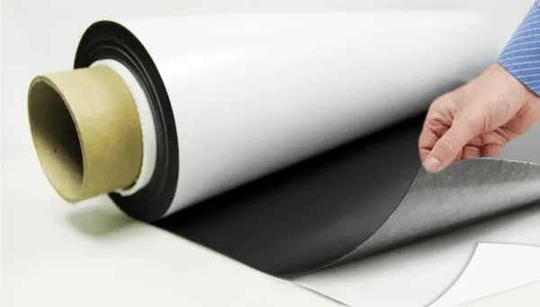 Mano de una persona separando el film protector del vinil adhesivo para ejemplificar la diferencia en instalación entre vinil magnético vs vinil adhesivo.